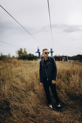 Young sexy man in leather jacket and sunglasses standing outdoor