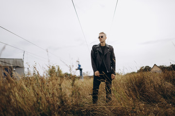 Young sexy man in leather jacket and sunglasses standing outdoor