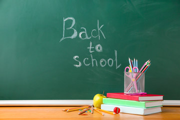 Set of school supplies on table in classroom