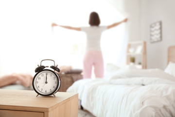 Alarm clock on table in bedroom of young woman