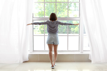 Fototapeta na wymiar Morning of beautiful young woman near window