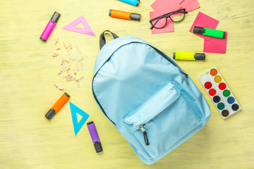 Backpack with school supplies on wooden background