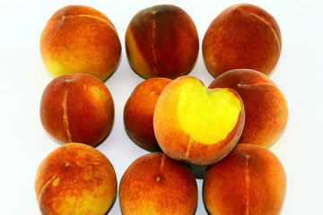 Nine peaches and a little of the bitten peach was lying on a white background