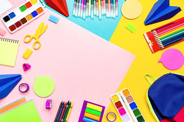 School supplies with colorful stationery. Markers, pencils, notebooks, backpack on multicolor background, copy space