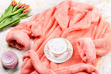 Flat lay composition with plush pink bathrobe, coffee, flowers on marble background, top view, copy...
