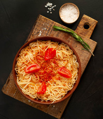 italian pasta spaghetti with tomato sauce, on a plate against the background of dark stone. View from above,