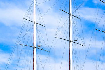 Ship masts and blue sky with clouds on background. 