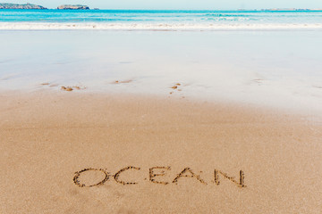 Ocean (inscription) on the beach (sand) by the sea or ocean. Summer mood concept.