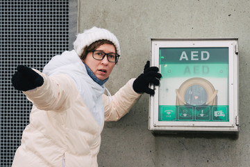 medicine cardiopulmonary resuscitation and emergency call. Young caucasian woman asking for help. device box aed automatic defibrillator for diseases