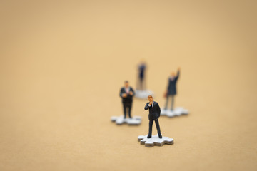 Miniature people businessmen standing on white Jigsaw. The concept used in selecting personnel to...