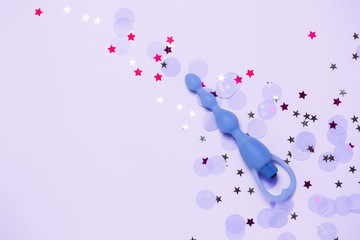 Adult sexy toy anal plug on pink background with confetti. Top view, flat lay.
