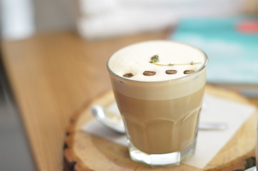 unusual glass cup of coffee styles with wooden table and served with the coffee beans