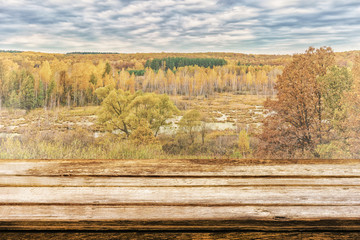 Naklejka na ściany i meble Empty wooden table with picturesque autumn landscape of view from the hill to the lowland with forest and swamps. Mock up for display or montage products