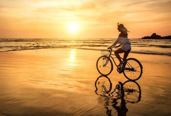 Naklejka na ściany i meble Happiness woman traveler with her bicycle rides on sea coastline