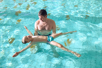 Happy father and son swimming lesson in the pool. Child learning