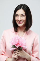 beautiful girl dressed in pink pajamas holding pink flower over white background