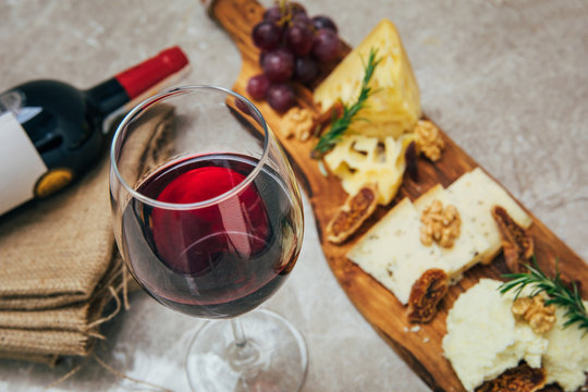 Glass of Wine and cheese. Assortment or various type of cheese, wine glass and bottle on the table in restaurant. Red, rose and yellow wine or champagne on the table. Winery concept image