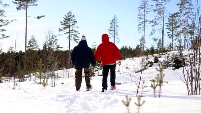 Loving couple trudges in unison through deep snow while wearing snow shoes