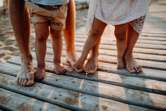 Legs And Feet Of Family Standing On Beach On Summer Holiday, A Midsection.