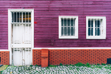 Building facade background with purple wood wall, red brickwork and white windows and a door on the street in Istanbul.