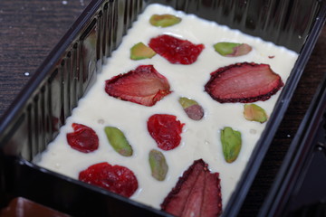 Homemade chocolate, decorated with dried fruit and pistachios. Poured into molds for curing. Next on the table are the ingredients.