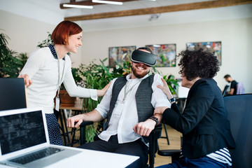 Group of young businesspeople with VR goggles in office, start-up concept.