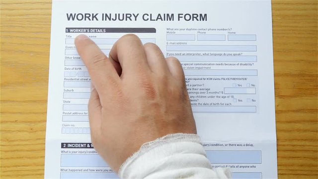 man with a wrap hand reading a work injury claim form