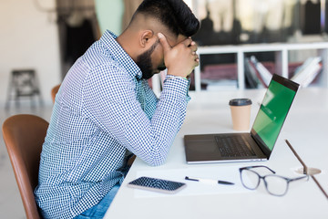 Tired and worried indian business man at workplace over laptop in office
