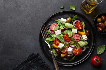 Fresh greek salad with tomato, cucumber, bel pepper , olives and feta cheese on black plate