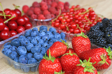 Mix of fresh berries on wooden background, strawberry, blueberry, raspberry,  blackberry, cherry and red currant