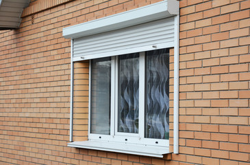 Rolling shutters brick house windows protection. Brick house with metal roller shutters on the...