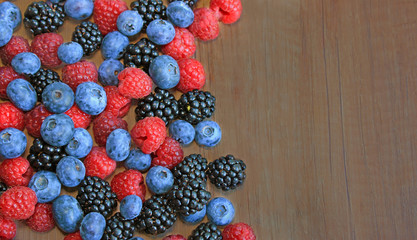 Mix of fresh berries on wooden background, blueberry, raspberry, blackberry