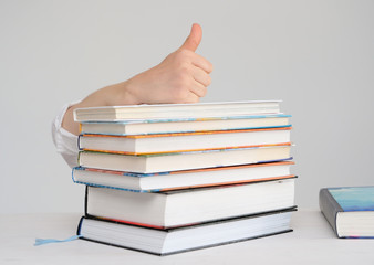 Child's hand is on a stack of books shows a thumb up
