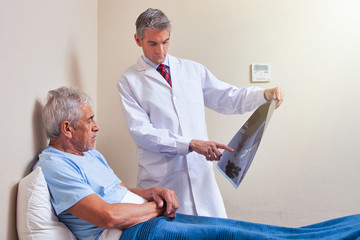 Obraz premium Senior adult in hospital bed with doctor analyzing xray scan
