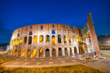 Fototapeta na wymiar ROME, ITALY - JUNE 2014: Tourists visit Colosseum at night. The city attracts 15 million people annually