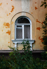 Fototapeta na wymiar Arch window on the ragged old wall