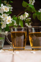 branch of blooming jasmine and two cups of tea