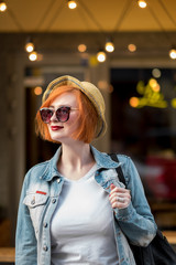 Young redhead woman standing by the street cafeteria. Traveling concept.