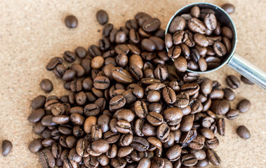 a handful of coffee beans and a spoon dispenser close up, top view