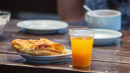 Orange juice in a plastic cup and a pie on the table