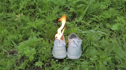 old Burning boots sports sneakers on the grass in the park. shoes burn in the forest - Powered by Adobe