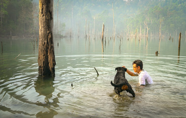 Man and dog playing and swimming in a lake.