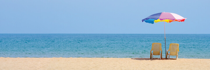 Summer background, chair and colorful umbrella on beach, sea and blue sky background with copy space, banner