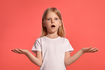 Close-up studio shot of a nice blonde little girl in a white t-shirt posing against a pink...