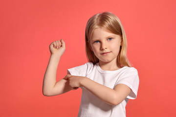 Close-up studio shot of a nice blonde little girl in a white t-shirt posing against a pink background.
