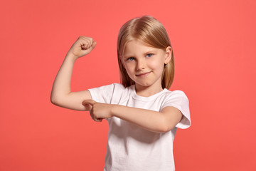 Close-up studio shot of a nice blonde little girl in a white t-shirt posing against a pink background.
