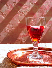 Glass with red with red wine with ice and fruits on a copper tray on sand background