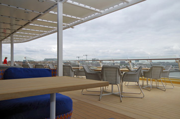 Außenbereich mit Terrasse und Sitzmöbeln auf Deck von Kreuzfahrtschiff mit Skyline von Hamburger...