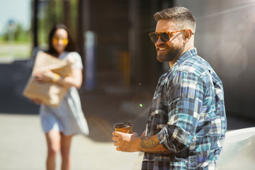 Young couple preparing for vacation trip on the car in sunny day. Woman and man shopping and ready for going to sea, riverside or ocean. Concept of relationship, vacation, summer, holiday, weekend.