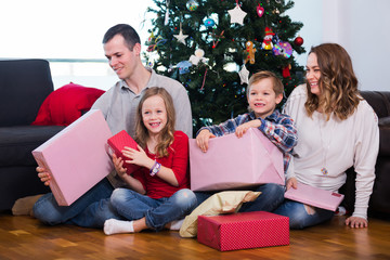 Smiling family members presenting gifts on Christmas